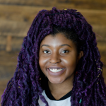 Headshot photo of Rizèl Scarlett. Rizèl is shown wearing purple faux locs.