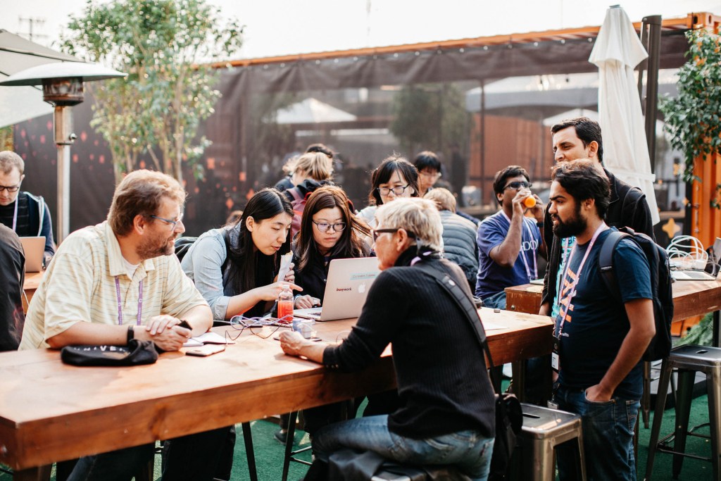 A group of Universe attendees sit around an outdoor table.