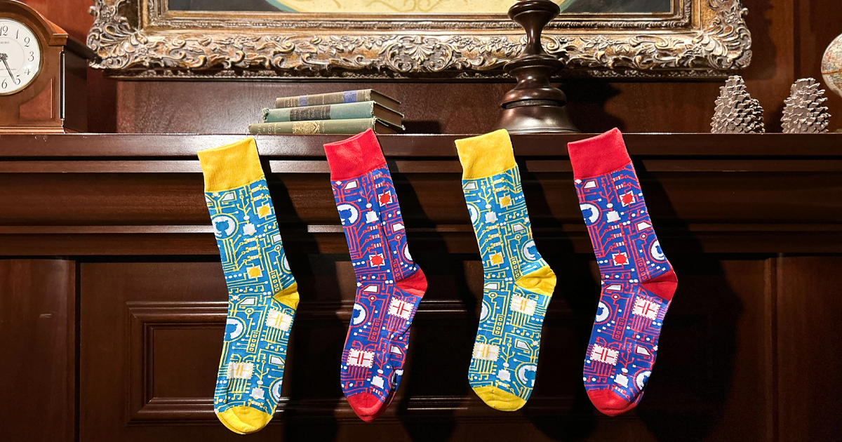 Four GitHub-branded socks in alternating colors hanging from a wooden mantel, like Christmas stockings.